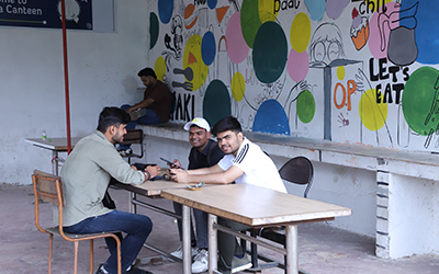 PGDM Students Networking and Relaxing in the IMS Noida Canteen Three students sitting in the canteen at IMS Noida, enjoying their time together and having a conversation.